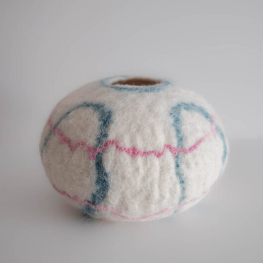 white woolen bowl with blue and pink decorative yarns